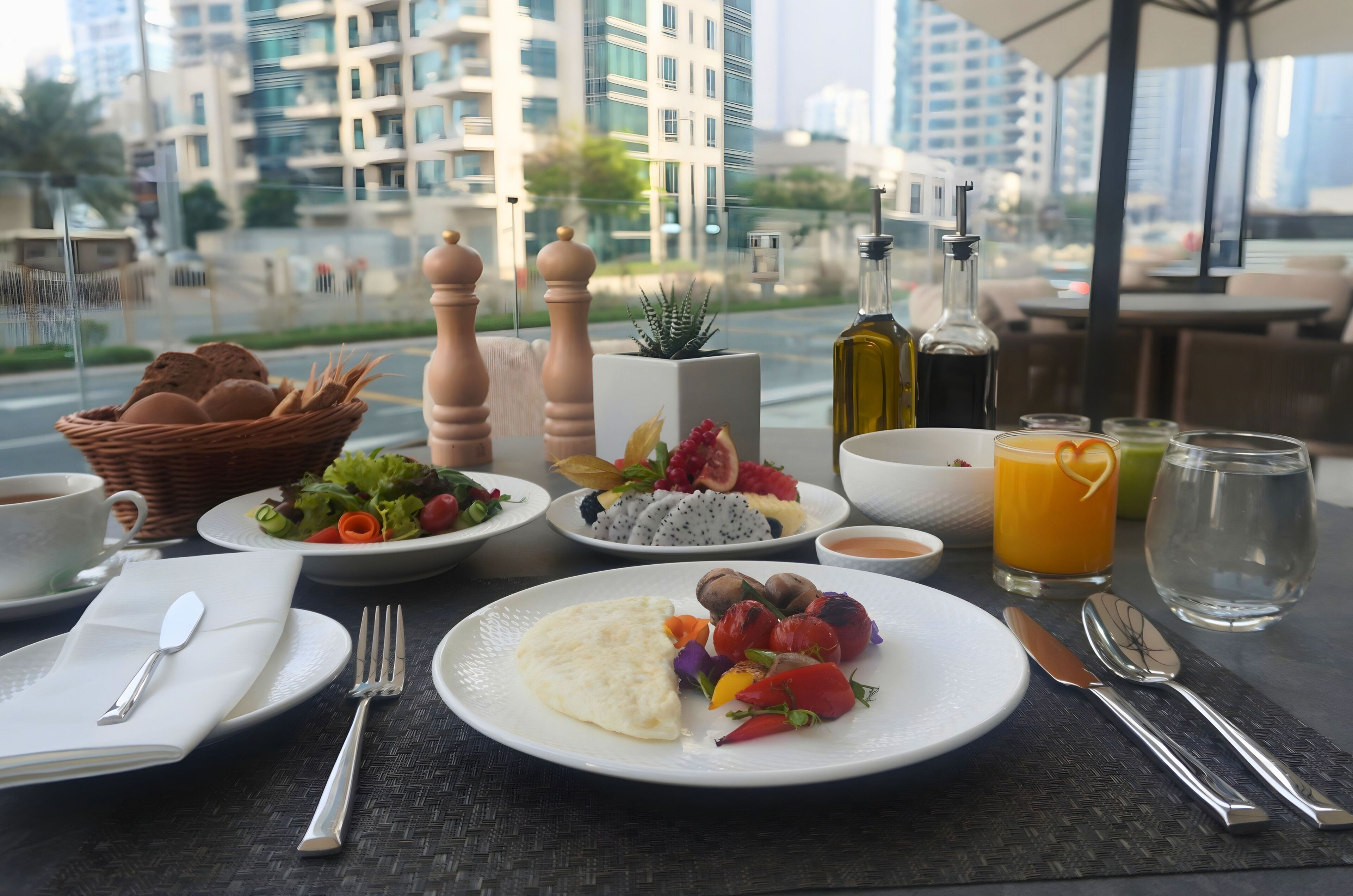 Una escena de desayuno con platos de comida, una cesta y vistas de edificios.