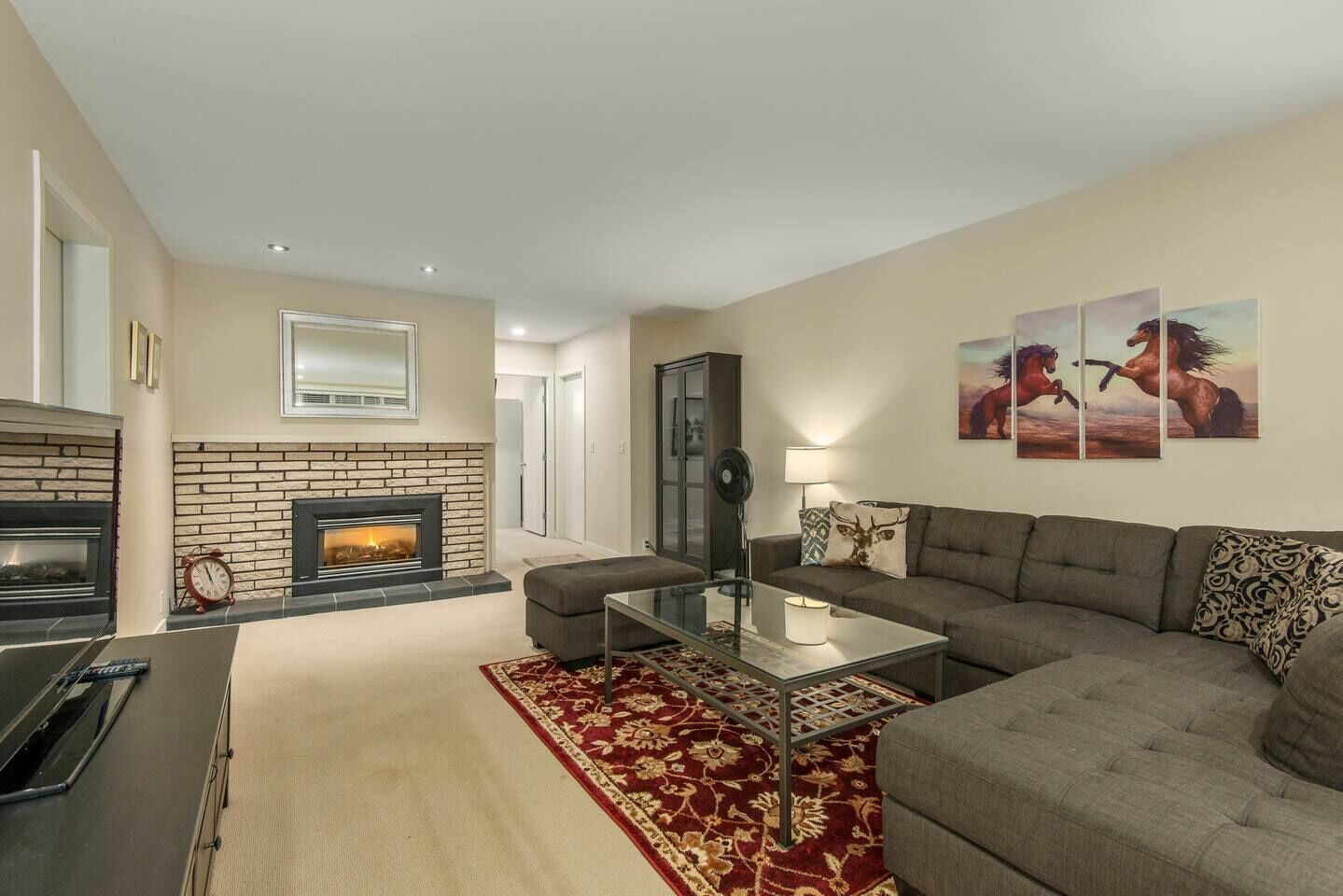 A living room with a fireplace, a sofa, a coffee table, and a rug.