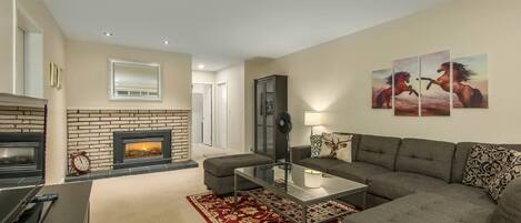 A living room with a fireplace, a sofa, a coffee table, and a rug.