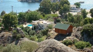 A coastal property with a pool, a wooden cabin, and rocky terrain. - Selenes Pansiyon (Milas)