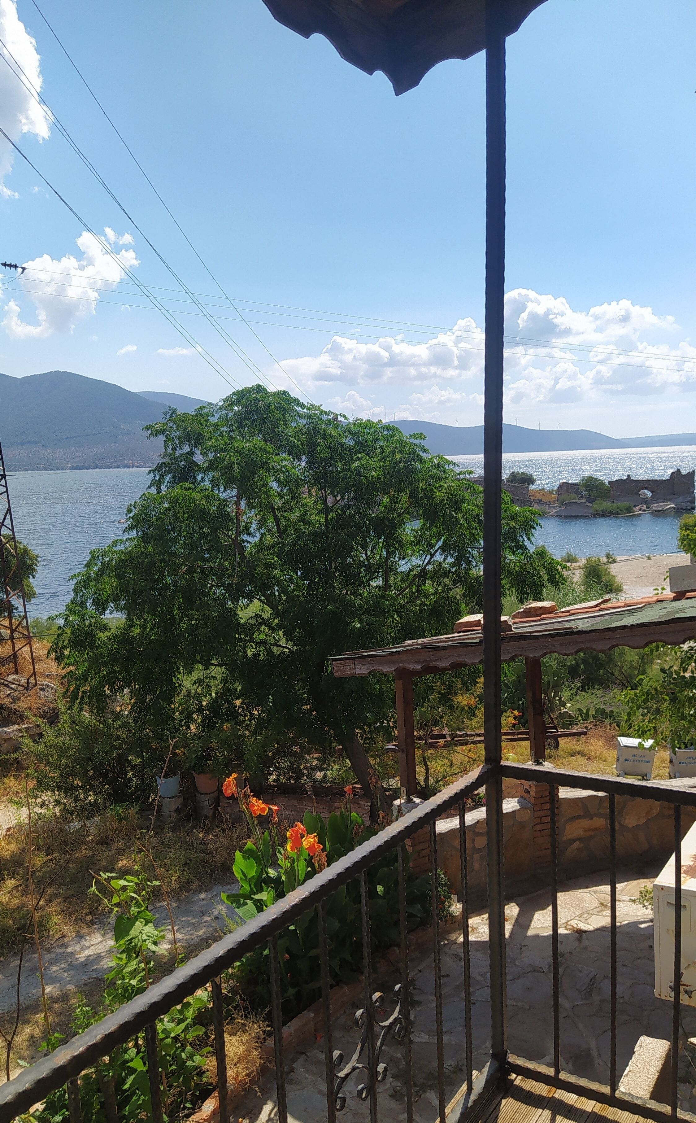 A balcony with a view of a lake, trees, and distant mountains.