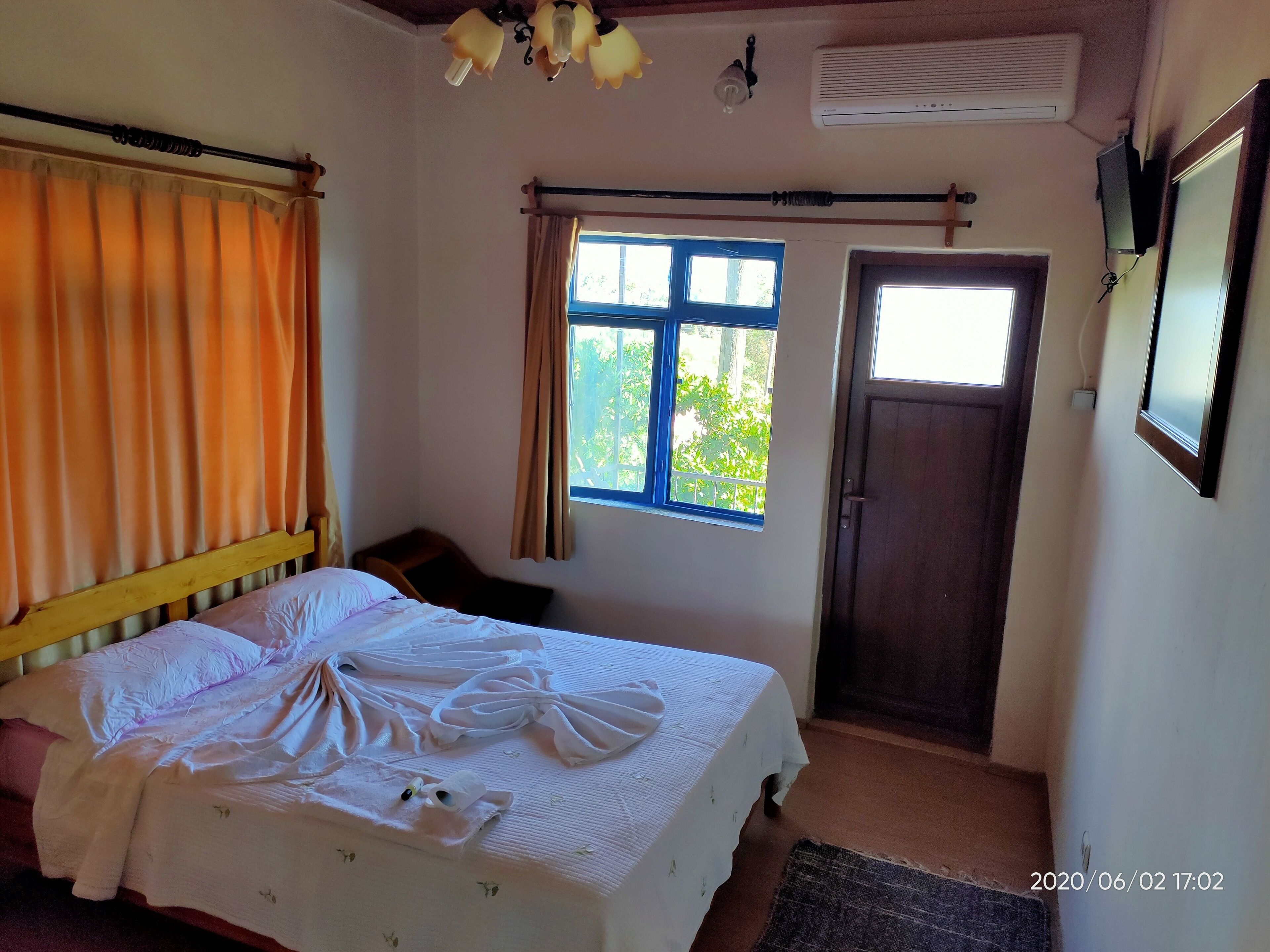 A bedroom with a bed, curtains, a window, and a door.