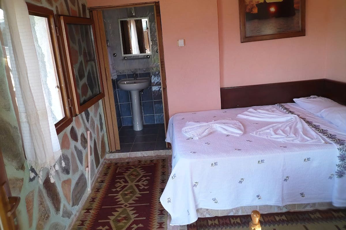 Quarto com cama, pia e espelho.
