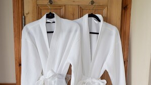 Dos batas blancas colgadas en una puerta de madera con un tirador de metal.