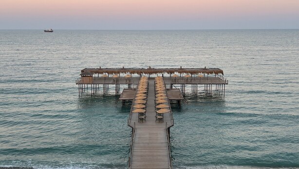A pier leading to an overwater bungalow with thatched umbrellas and wooden tables. - Igneada Resort Hotel & Spa  (Demirköy)