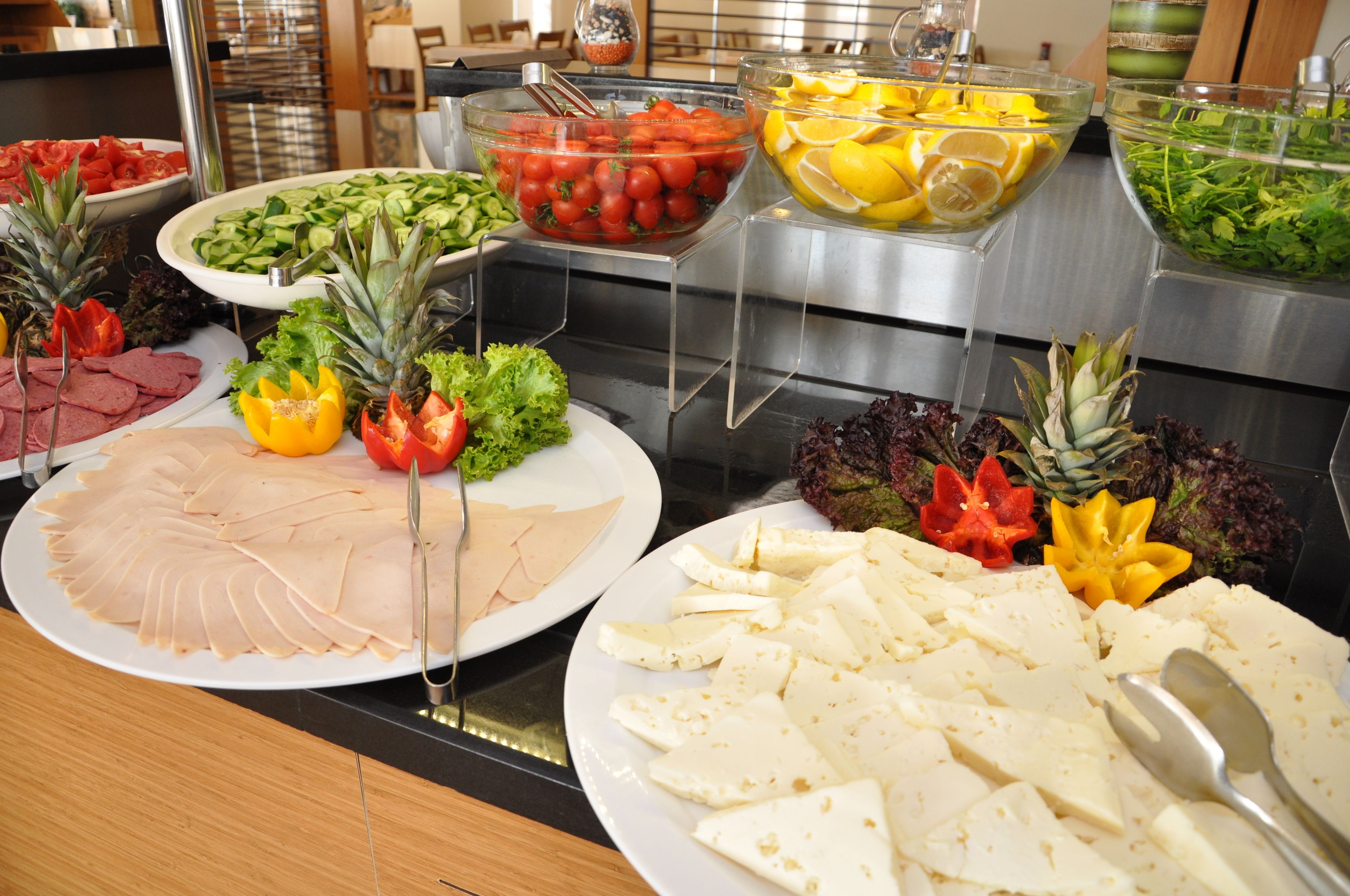 A buffet with various food items including meats, cheeses, fruits, and vegetables.