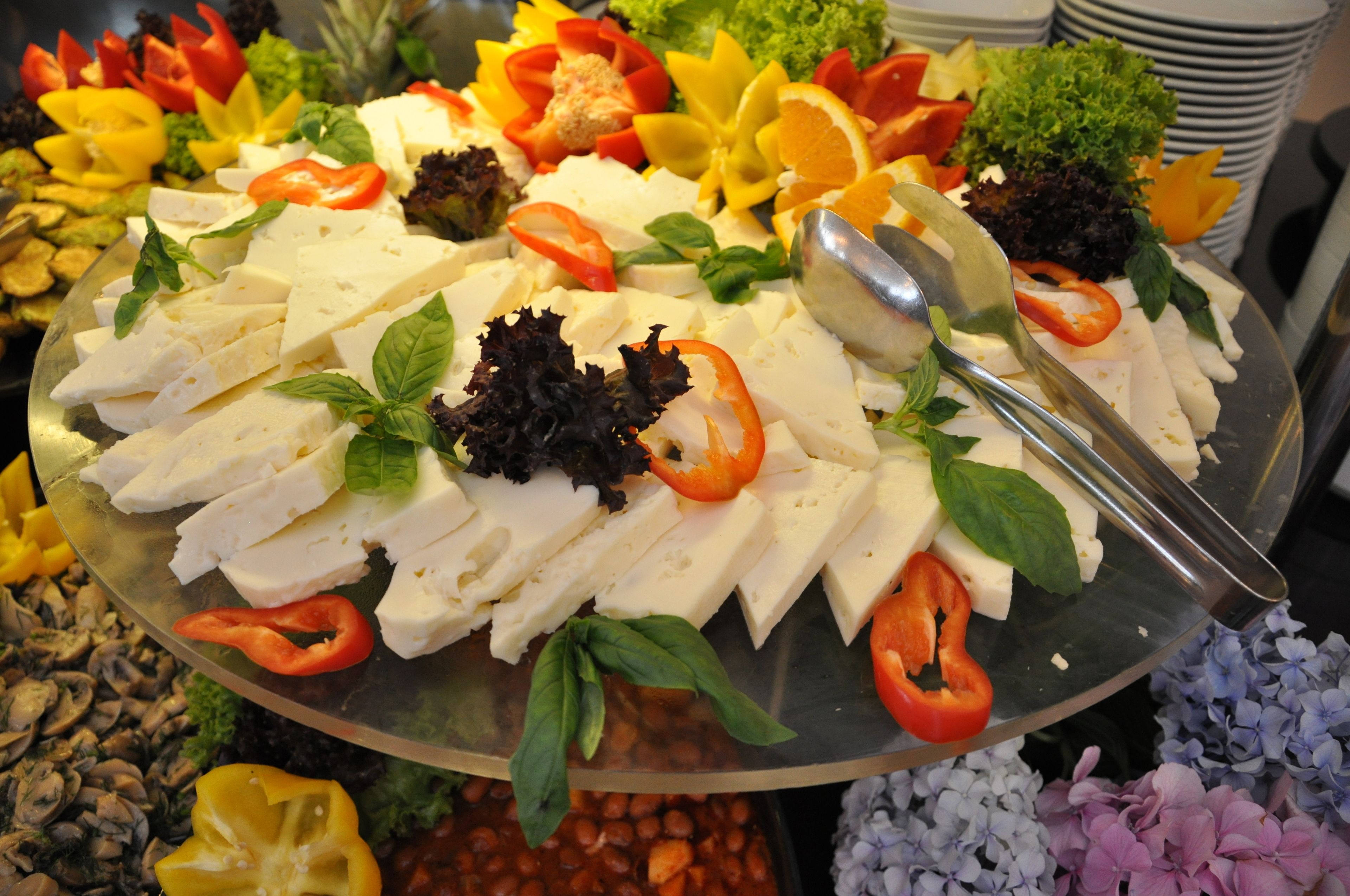 Un bufé con diversos quesos, verduras y frutas.