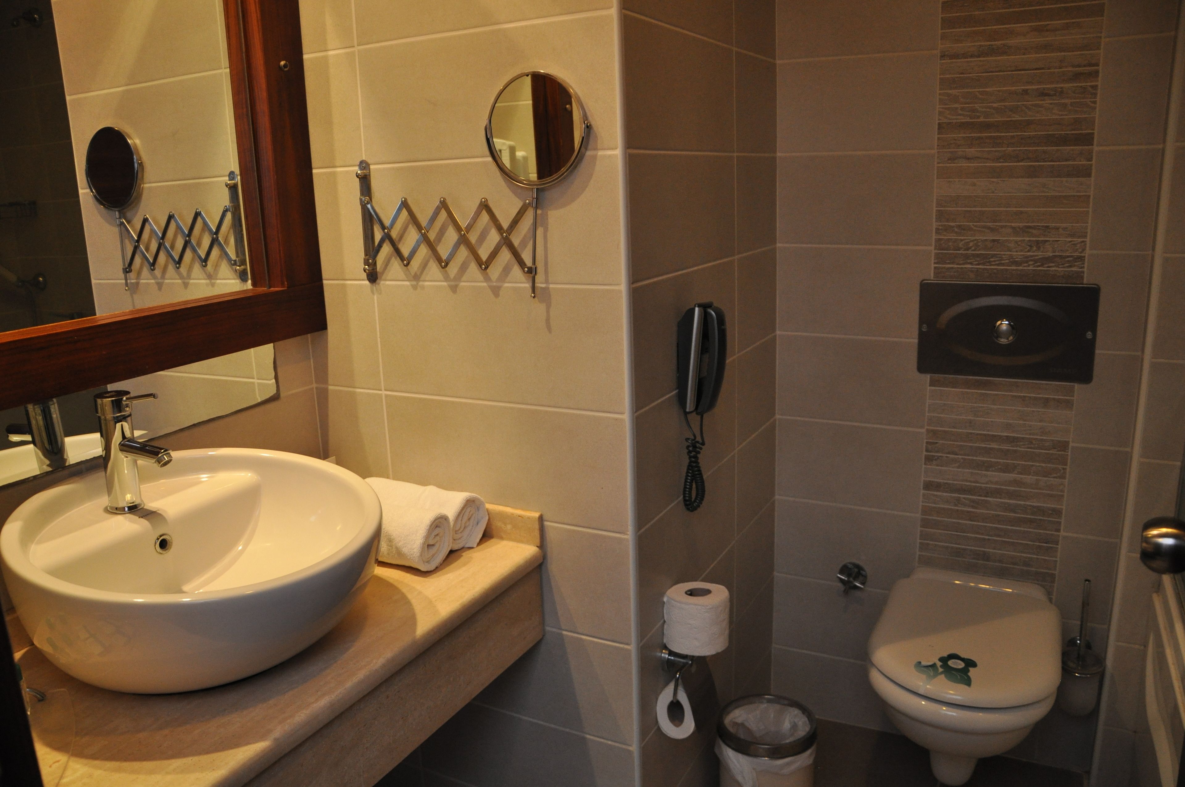 Un baño con lavamanos, espejo, inodoro y teléfono.