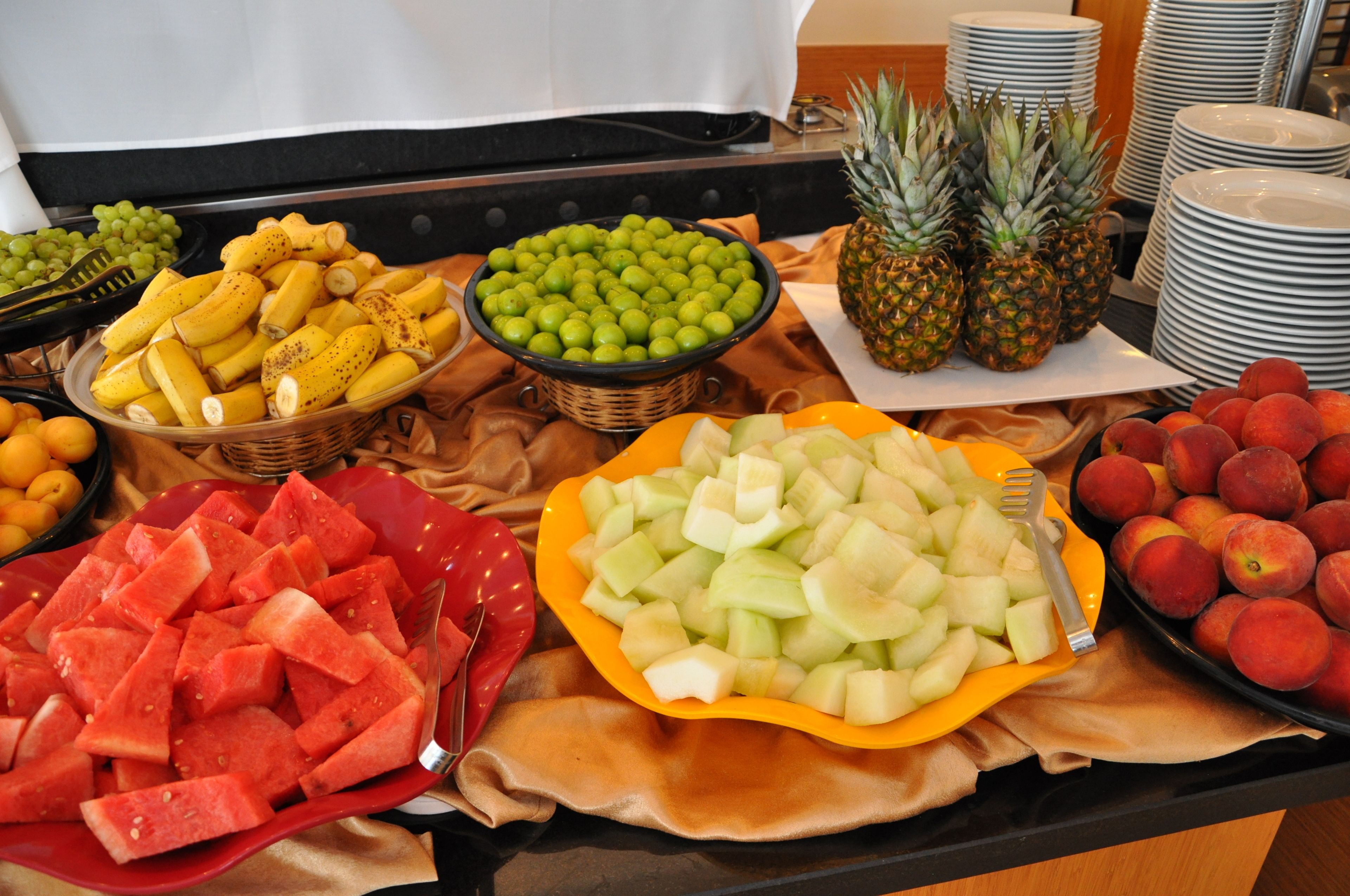A buffet table with various fruits and vegetables, including watermelon, pineapple, and peaches.