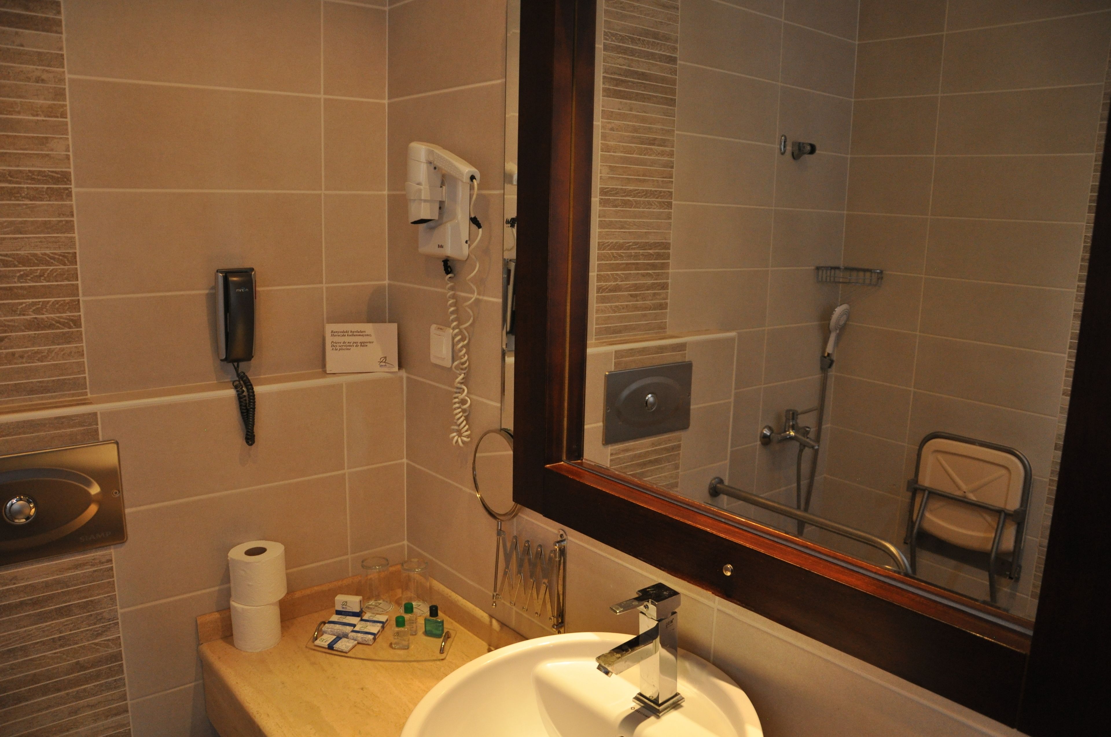 Un baño con lavamanos, espejo y zona de ducha.