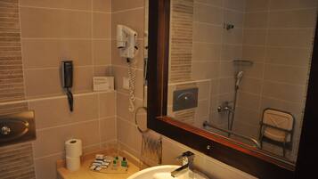 Un baño con lavamanos, espejo y zona de ducha.