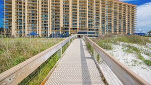A long, narrow wooden boardwalk leading to a large, multi-story hotel with balconies. - Two bedroom Condo 909 at Phoenix 5 (Orange Beach)