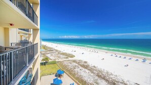 A beachfront hotel with balconies, a sandy beach, and a clear blue sky. - Two bedroom Condo 909 at Phoenix 5 (Orange Beach)