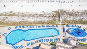 A pool area with multiple sun loungers and a large swimming pool. - Two bedroom Condo 909 at Phoenix 5 (Orange Beach)