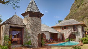 A stone building with a tower, a swimming pool, and a covered patio area. - Villa Piton Caribbean Castle | Enhanced cleaning measures. CERTIFIED TO HOST!!! (Soufriere)