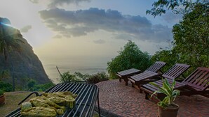 A patio with a grill, lounge chairs, and a potted plant. - Villa Piton Caribbean Castle | Enhanced cleaning measures. CERTIFIED TO HOST!!! (Soufriere)