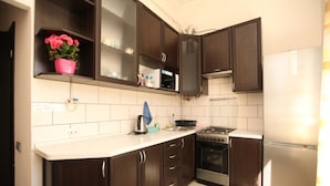 Une cuisine moderne avec des meubles en bois foncé, un réfrigérateur en acier inoxydable, une cuisinière à gaz et un four à micro-ondes.