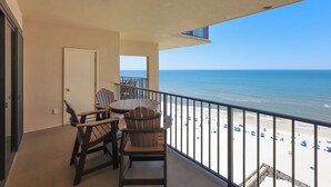 A balcony with a view of the beach, a table with chairs, and a door. - Three Bedroom on the BEACH - Phoenix II 2141 (Orange Beach)