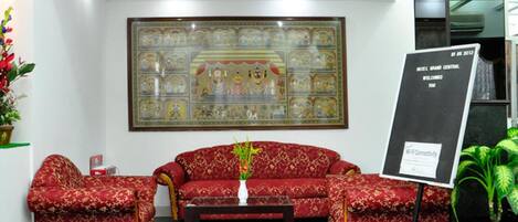 A reception area with a red sofa set, a coffee table, and a large framed artwork on the wall.