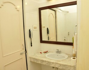 Bathroom features a sink, mirror, and toilet with a towel rack and telephone.