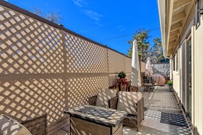 An outdoor patio with wicker furniture, a lattice fence, and a clear blue sky. - CENTRALLY LOCATED Zen Hideaway: Private Hot Tub & Walk to Trails! (Sedona)
