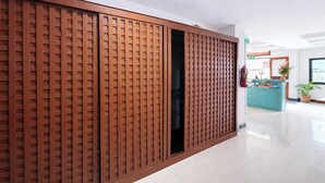 Um hall de hotel moderno com uma porta deslizante de madeira, um balcão de recepção e um vaso de planta.