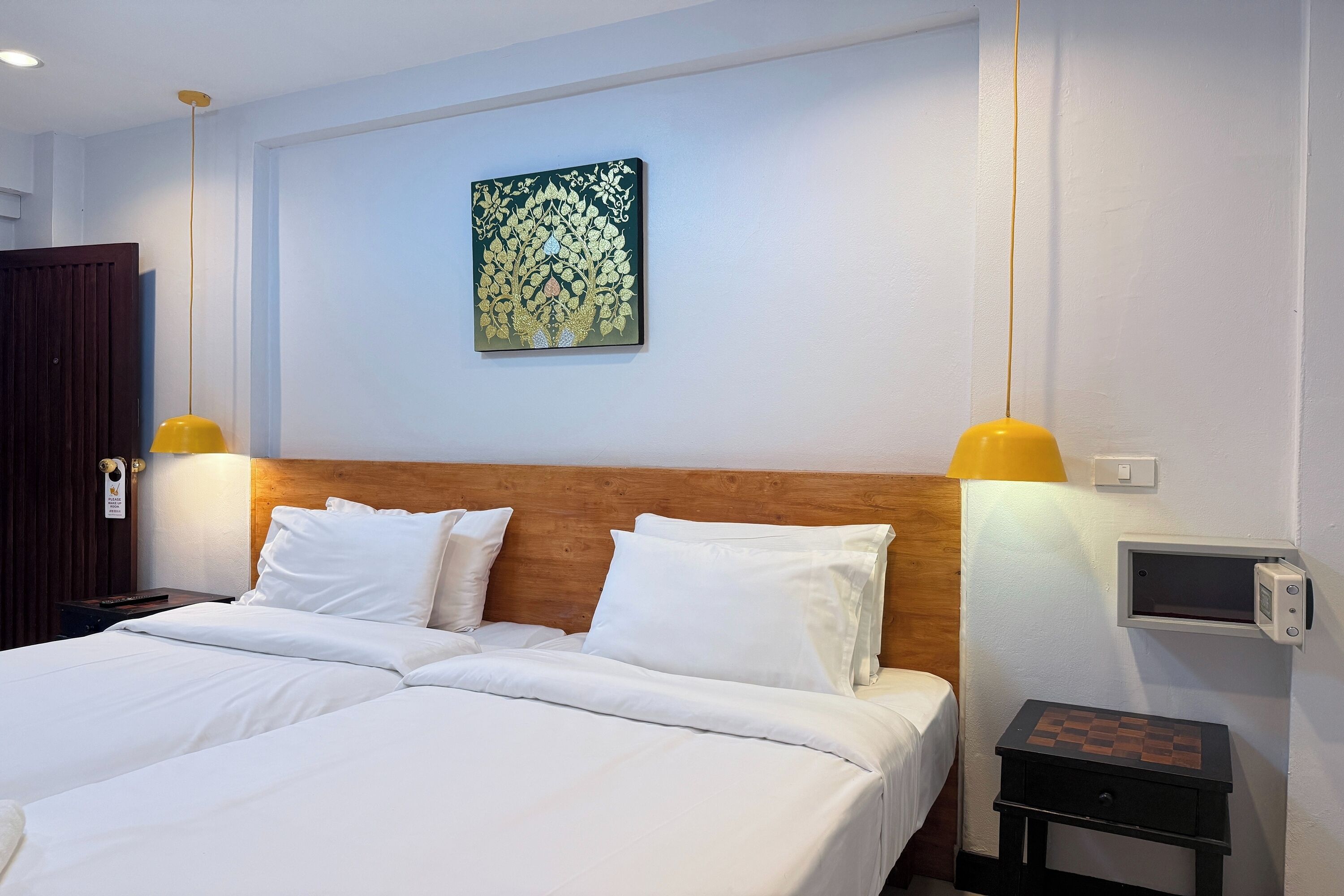 A hotel room with a double bed, two bedside lamps, a wooden headboard, a wall-mounted TV, and a chessboard on a small table.