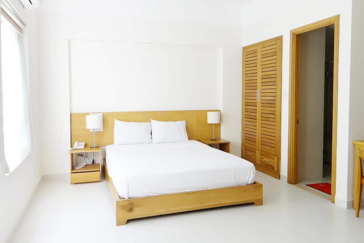 Ein Schlafzimmer mit einem hölzernen Bett, weißer Bettwäsche, zwei Nachttischlampen, einem Telefon am Nachttisch und einem Holzschrank.