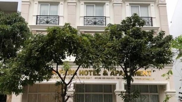 Un hôtel à la façade classique, doté d’une grande entrée avec une porte en verre et d’un espace extérieur aménagé avec des sièges.