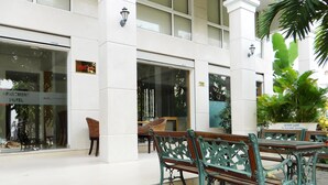 Une vue de l’extérieur d’un hôtel, avec une entrée fermée, un banc et un pot de fleurs.