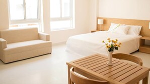 Une chambre d’hôtel avec un lit, un canapé, une table en bois et un vase de fleurs.