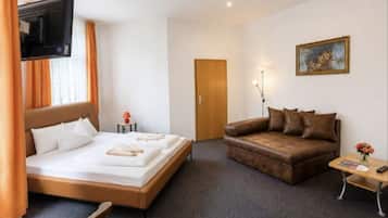 Ein Hotelzimmer mit einem Bett, einer Couch, einem Fernseher, einem Gemälde und einer Tür.