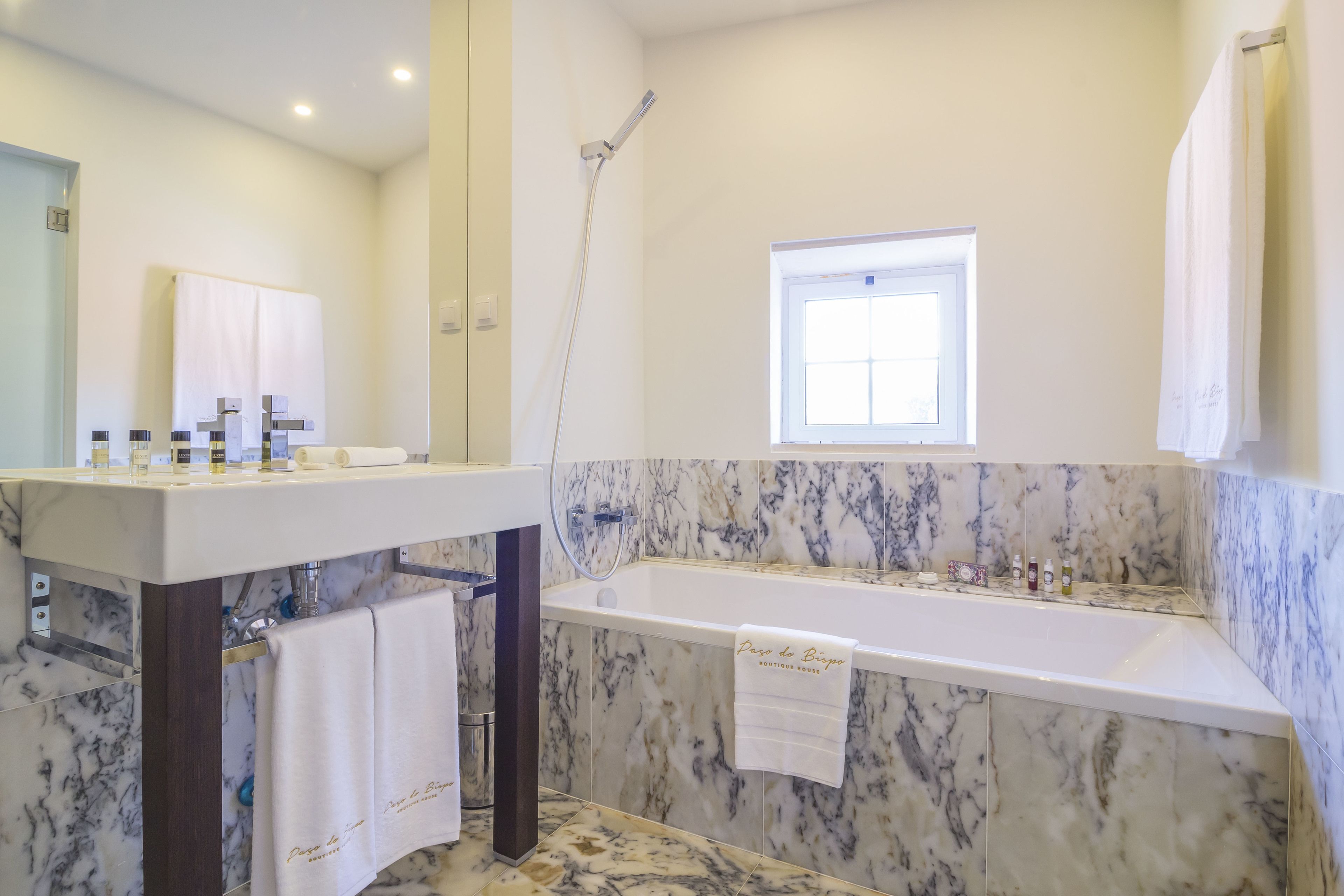 Een moderne badkamer met een marmeren wastafel, een badkuip en een douche.