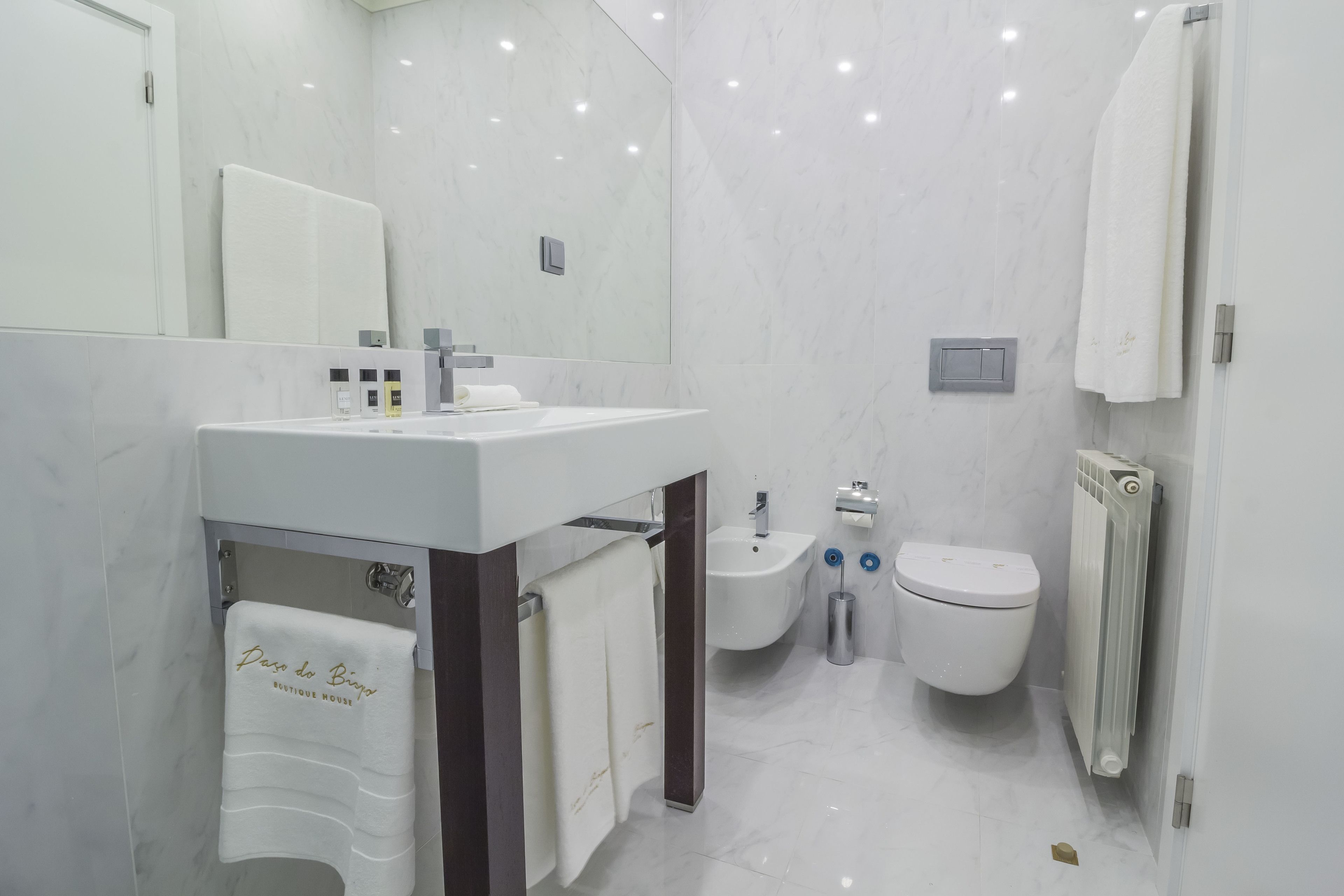 A modern bathroom with a white sink, mirror, and toilet.