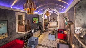 A spacious lobby with a high ceiling, a bar area, and a seating area with red and blue sofas. - Paço do Bispo Boutique House (Cascais)