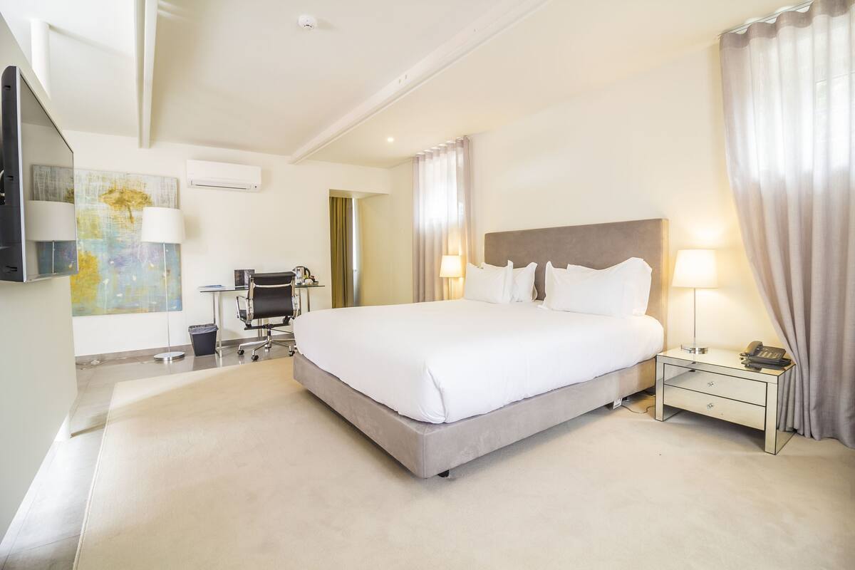 Een moderne hotelkamer met een groot bed, nachtkastjes, een bureau en een stoel.