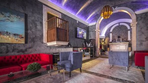 A modern interior with a red sofa, a blue armchair, and a glass coffee table. - Paço do Bispo Boutique House (Cascais)