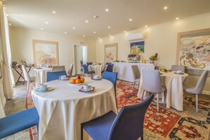 A dining area with round tables, chairs, and a carpeted floor.