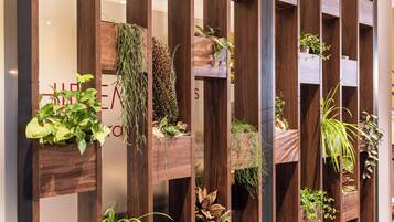 Pared vertical de madera con macetas con diversas plantas y un letrero con letras rojas.