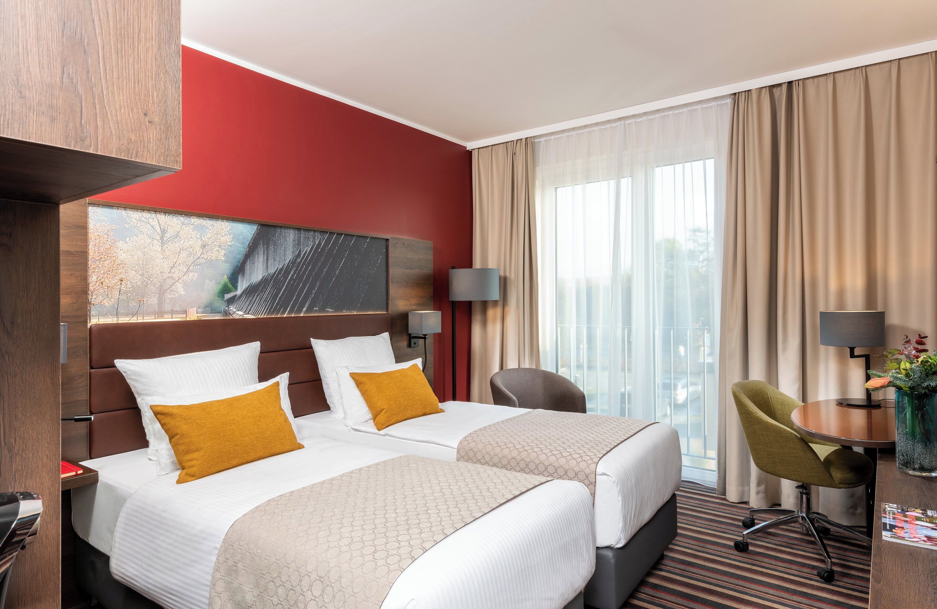 Une chambre d’hôtel avec deux lits, un bureau, une chaise et une grande fenêtre avec des rideaux.