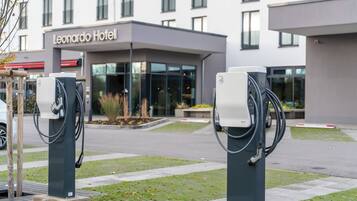 Due stazioni di ricarica per veicoli elettrici di fronte a un hotel dal design moderno.