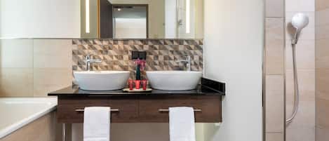 Une salle de bain moderne avec deux lavabos, un grand miroir et un espace douche.