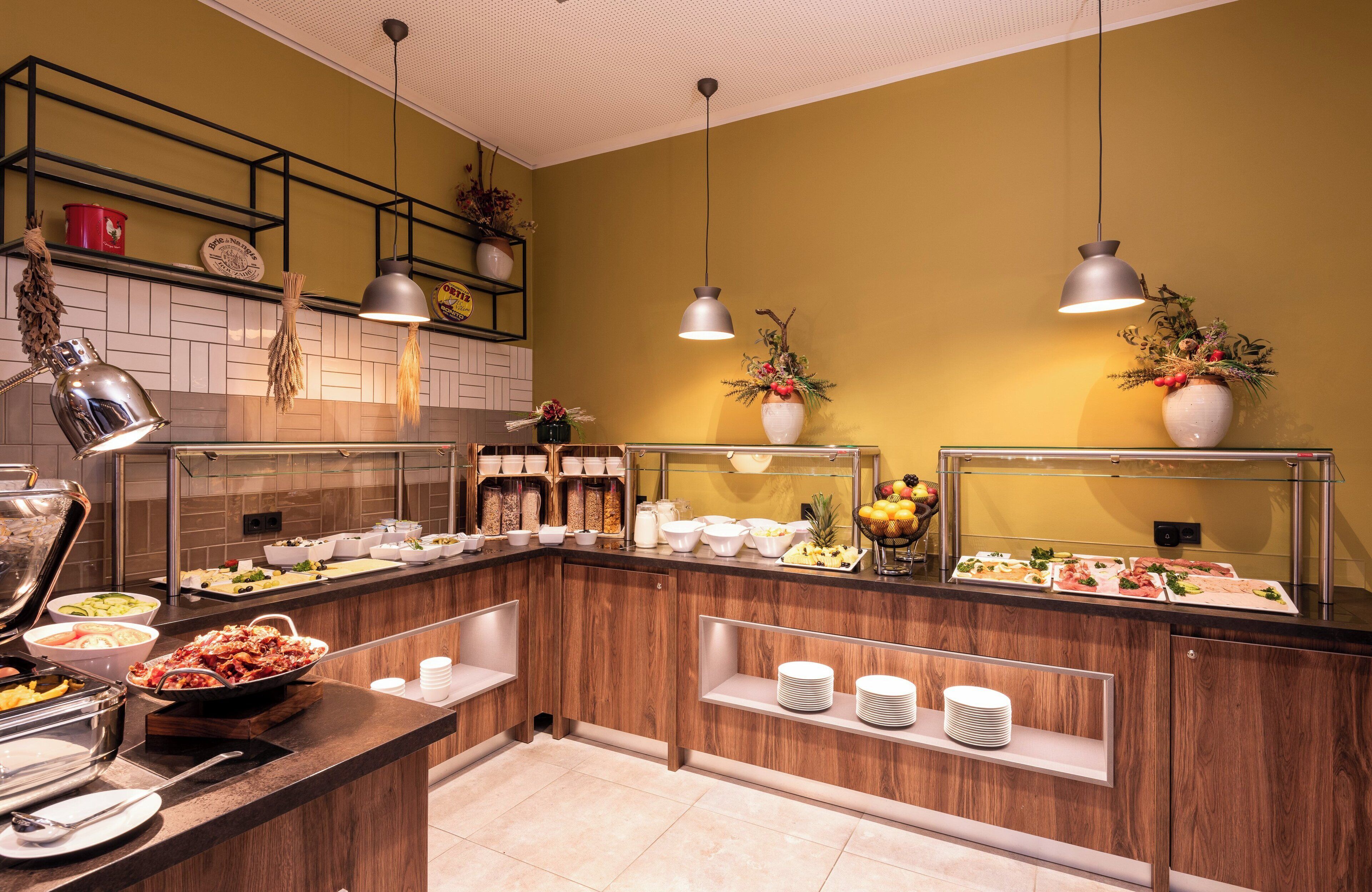 Een buffetopstelling met diverse gerechten en serveerschaaltjes, een houten toonbank en hangende pendantlampen.