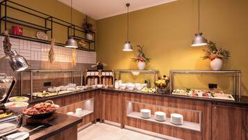 A buffet setup with various food items and serving dishes, a wooden counter, and hanging pendant lights.