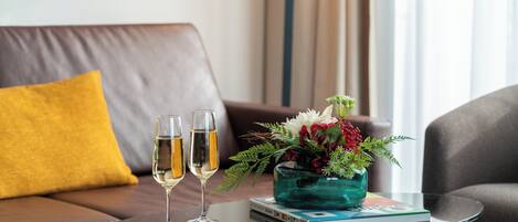 A glass table with two champagne flutes, a book, and a vase with flowers.