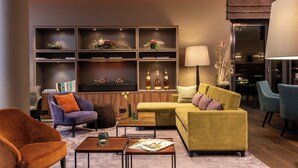 Una sala de estar moderna con un sofá, sillones, una mesa de centro y una estantería con objetos decorativos.