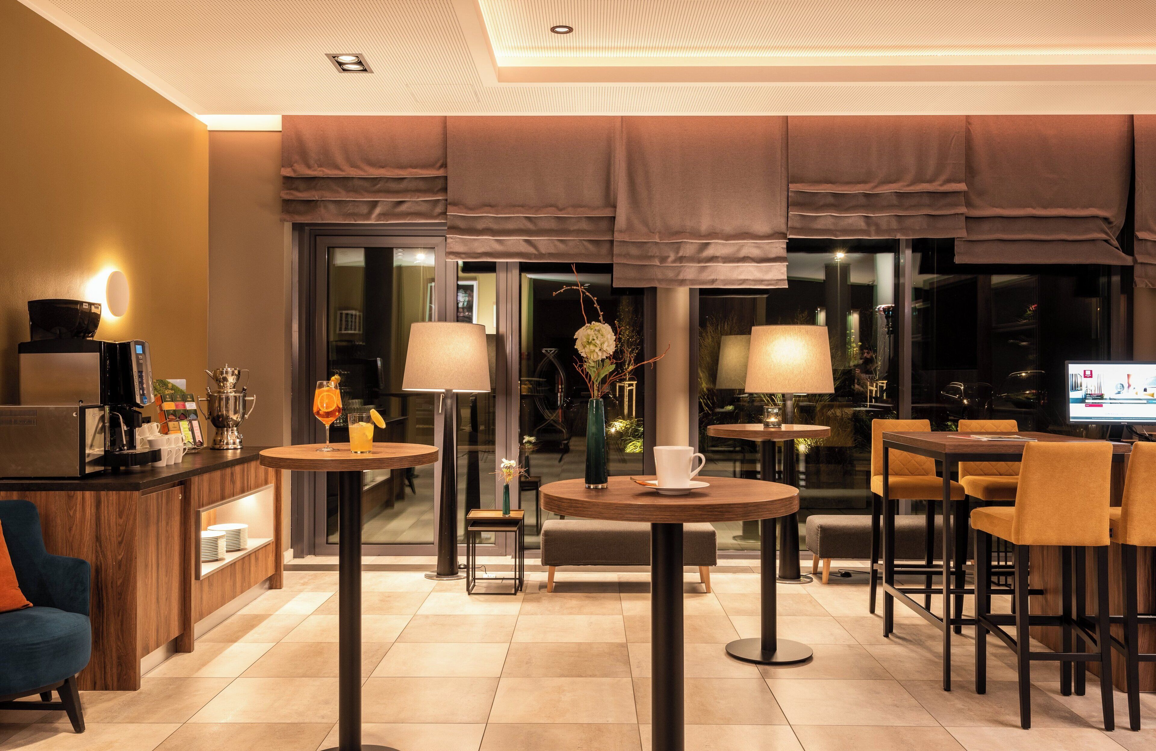 A modern hotel lobby with a bar area, seating arrangements, and a television screen.