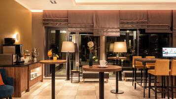 Un moderno vestíbulo de hotel con zona de bar, disposición de asientos y una pantalla de televisión.