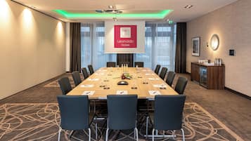 Une salle de conférence équipée d’une longue table, de chaises et d’un écran de projection affichant le logo de Leonardo Hotels.