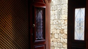 An arched doorway leading to a courtyard with a stone wall and a wooden door with a decorative metal design. - Auberge 32 | Old Town (Rhodes)